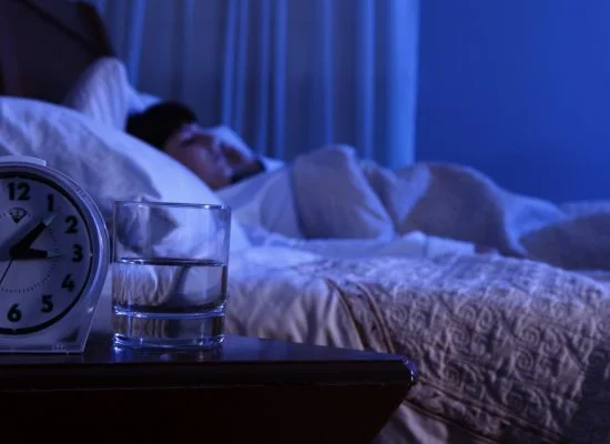Person lying awake in bed at night with racing thoughts.